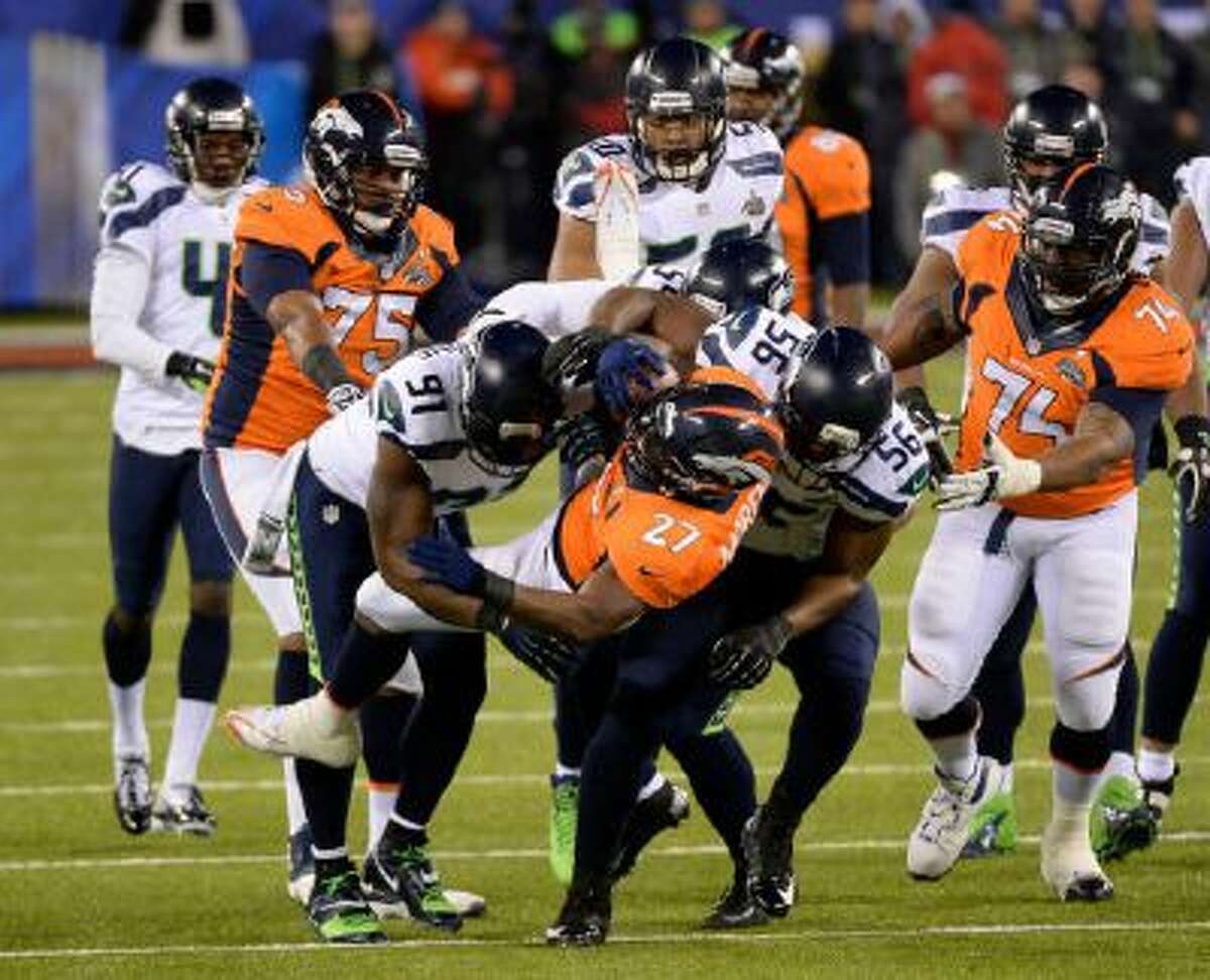 Denver Broncos running back Knowshon Moreno (27) gets hit hard during the first quarter. The Denver Broncos vs the Seattle Seahawks in Super Bowl XLVIII at MetLife Stadium in East Rutherford, New Jersey Sunday.