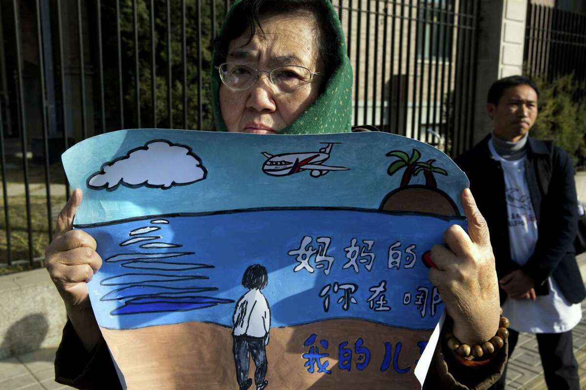 A woman whose son was on board the missing Malaysia Airlines Flight 370 protests with a banner which reads “Mother’s heart is broken, where are you my son” near the Malaysian Embassy in Beijing on the one year anniversary, Sunday.