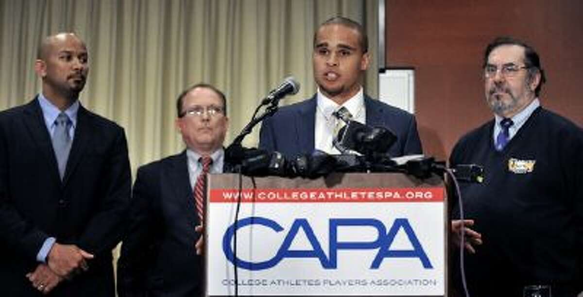 Northwestern quarterback Kain Colter second from right, speaks while College Athletes Players Association president Ramogi Huma left, United Steel Workers National Political Director Tim Waters second from left, and United Steel Workers president Leo Gerard right, look on during a news conference in Chicago, Tuesday.