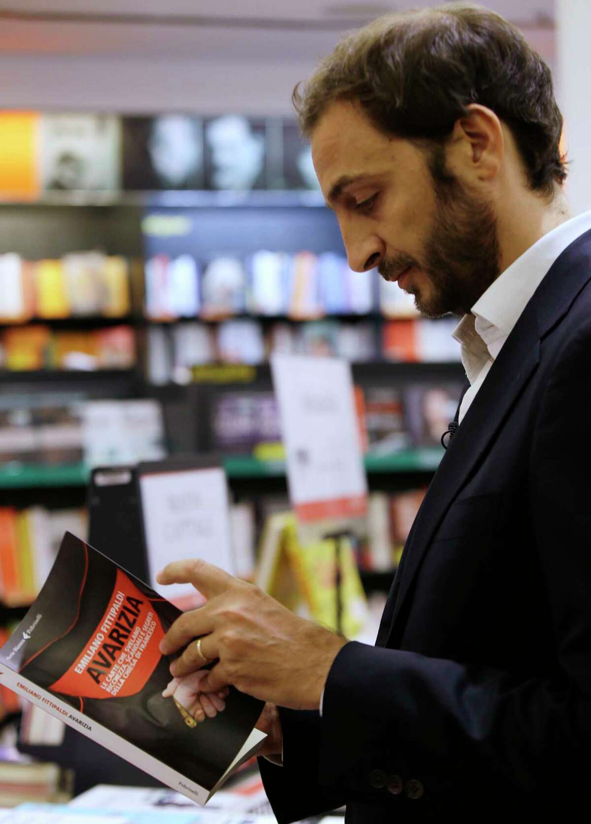 Italian journalist Emiliano Fittipaldi browses through his book titled " Avarice" during an interview with The Associated Press, in a Rome's bookstore, Tuesday, Nov. 3, 2015. The Vatican's new leaks scandal intensified Tuesday with two books detailing the mismanagement and internal resistance that is thwarting Pope Francis' financial reform efforts: 'Avarice' by L'Espresso Vatican reporter Emiliano Fittipaldi and 'Merchants in the Temple' by Italian journalist Gianluigi Nuzzi. (AP Photo/Gregorio Borgia)