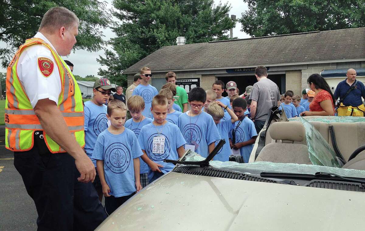 Cromwell Fire Chief Stephen Pendl and other Cromwell firefighters show Cub Scouts from six troops including Pack 9 of Cromwell the aftermath of a car extrication Tuesday morning at Pierson Park.