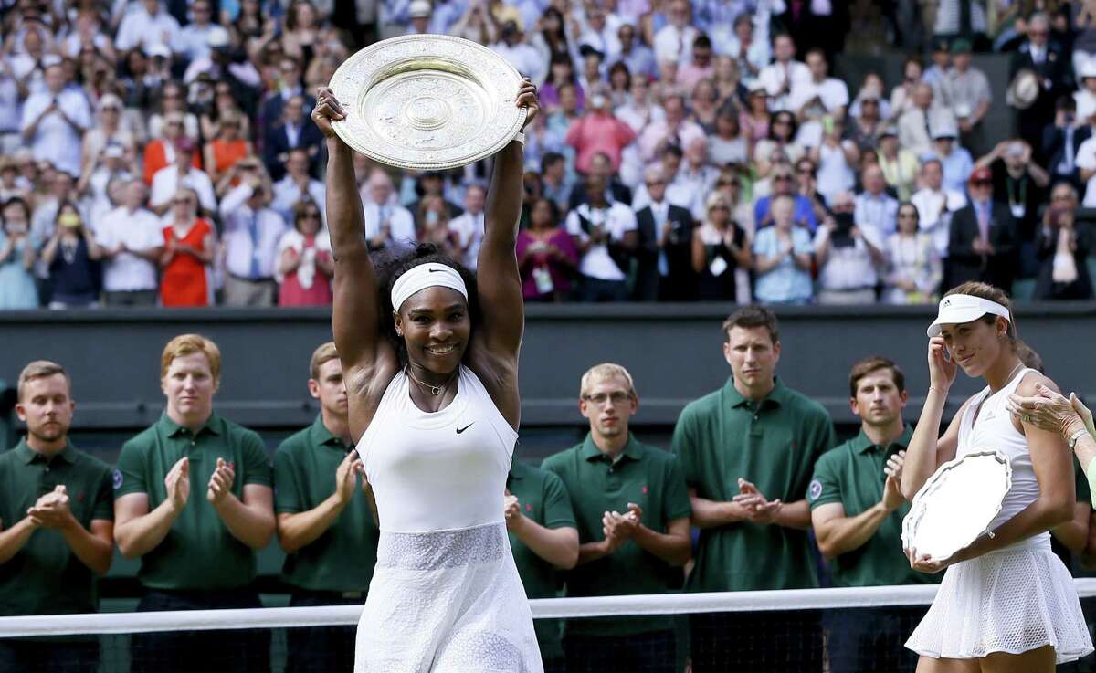 Serena Williams holds up the trophy after winning the final against Garbine Muguruza, background, on Saturday at the All England Lawn Tennis Championships in Wimbledon, London. Register sports columnist Chip Malafronte says Serena is, hands down, the greatest female athlete of all time.