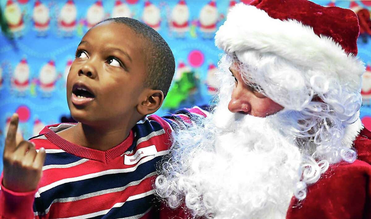 (Catherine Avalone - New Haven Register) Maurice Carrington, 7, of Hamden sits on the lap of a "sensitive" Santa who meets with children on the autisim spectrum one on one in a low-stimuli setting at a holiday party, Saturday, December 19, 2015, at ASD Fitness at 307 Racebrook Road in Orange. Carrington said, "Santa said I'm a very good boy. I love it here."