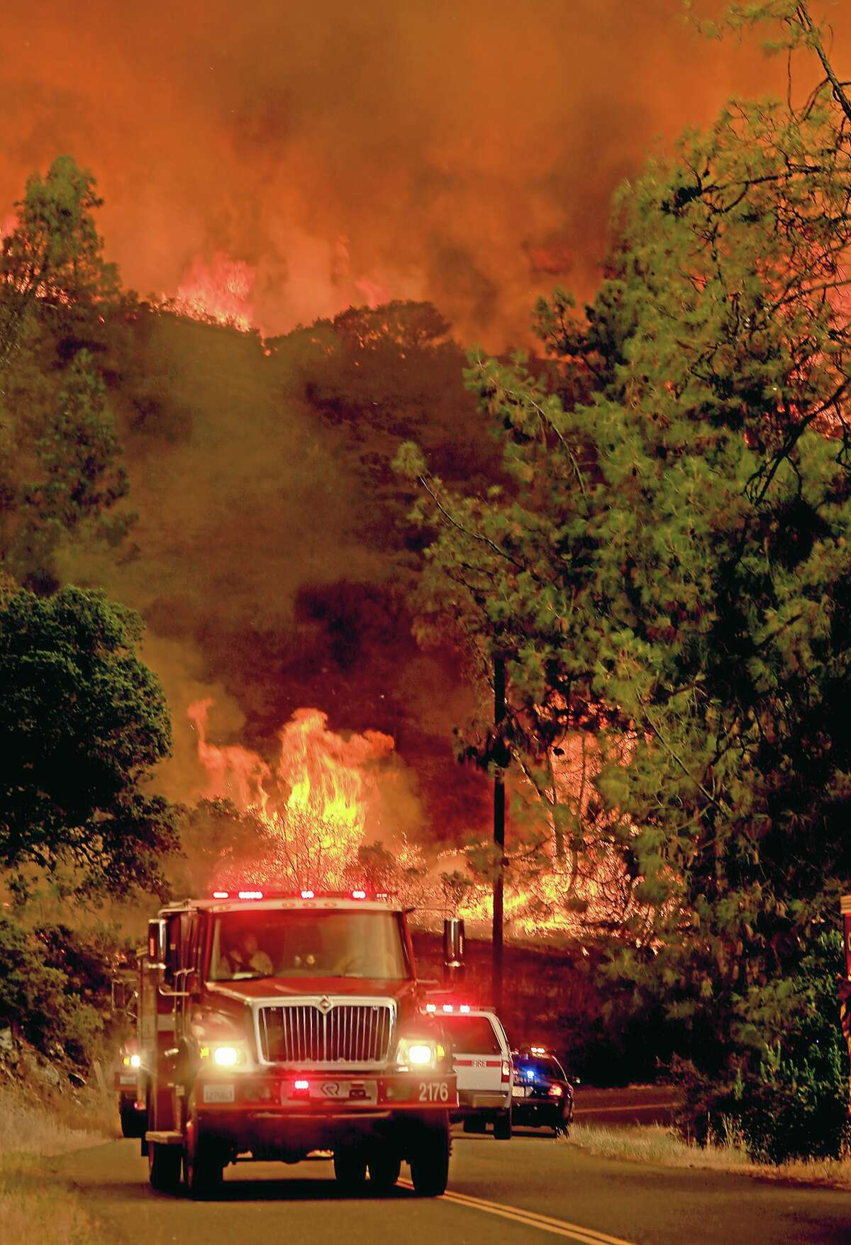 Fire personnel pull back from a wall of flames as it jumps Butts Canyon Road and Snell Valley Road, Tuesday, July 1, 2014, outside Middletown, Calif., near the border between Lake and Napa counties. By early evening 140 homes were evacuated and 2,500 acres were burned.