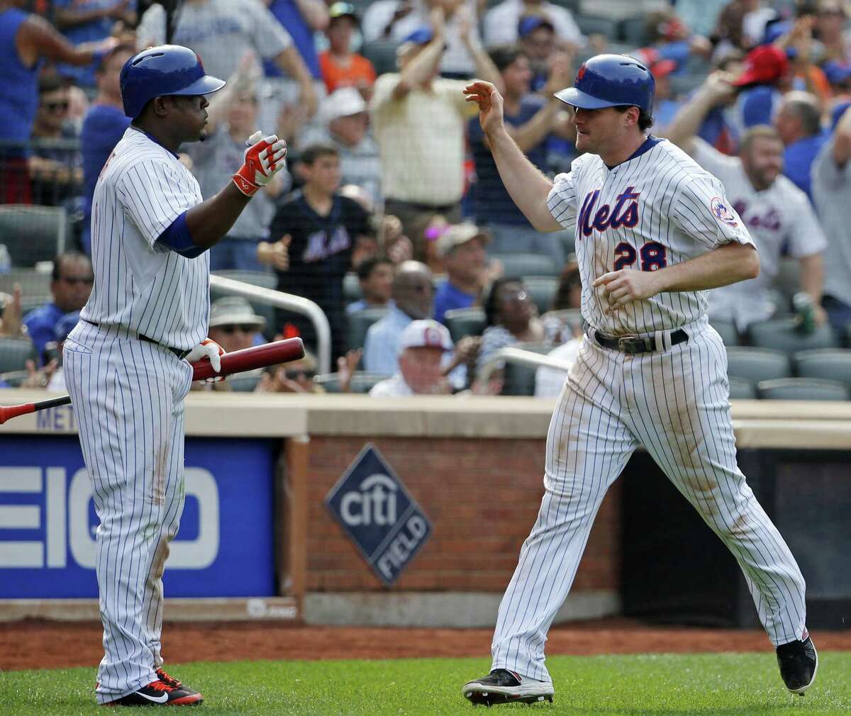 The Mets’ Juan Uribe, left, greets Mets Daniel Murphy after Murphy scored the go-ahead run in the seventh inning on Sunday.