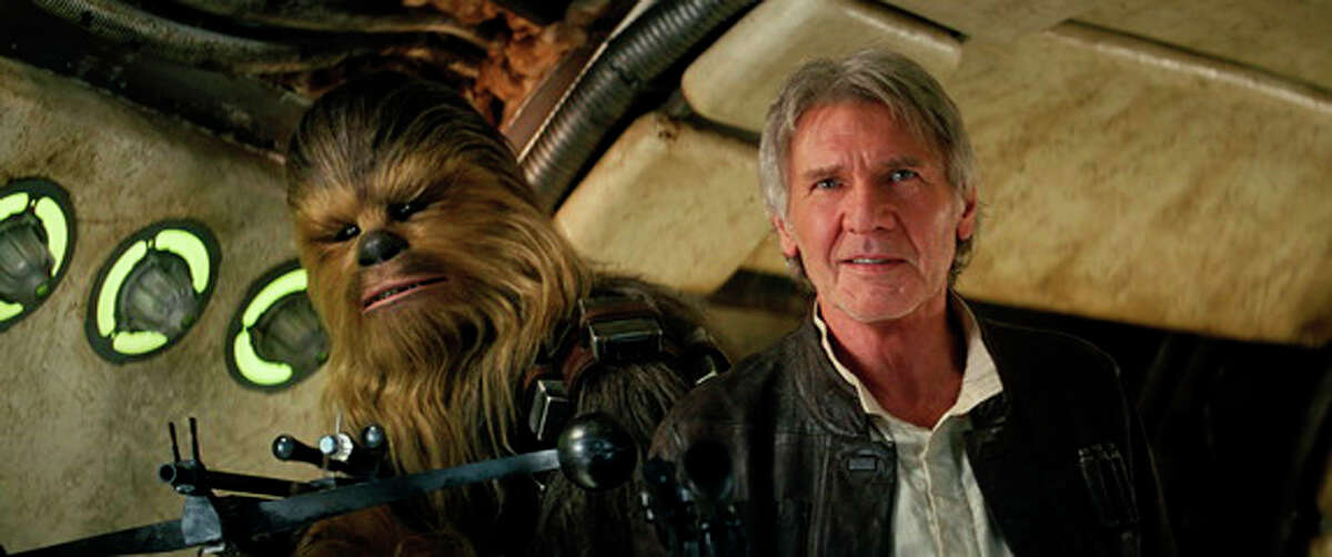 This photo provided by Lucasfilm shows Peter Mayhew as Chewbacca and Harrison Ford as Han Solo in “Star Wars: The Force Awakens.”