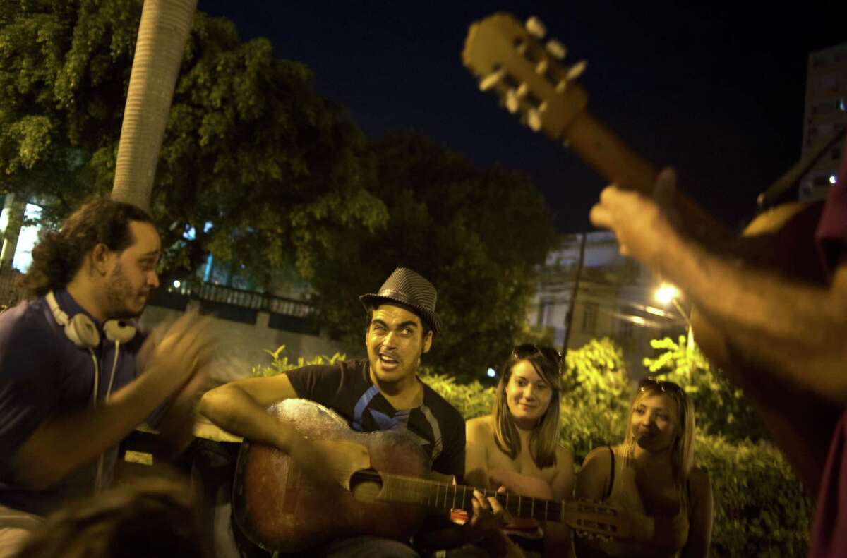 Youths sing and play music as they hang out in a park in Havana, Cuba, late Friday, Dec. 19, 2014. For a generation that grew up believing the best way to pursue their dreams was to leave the island, the announcement this week that Cuba will open relations with the U.S. is prompting many to reevaluate their futures.