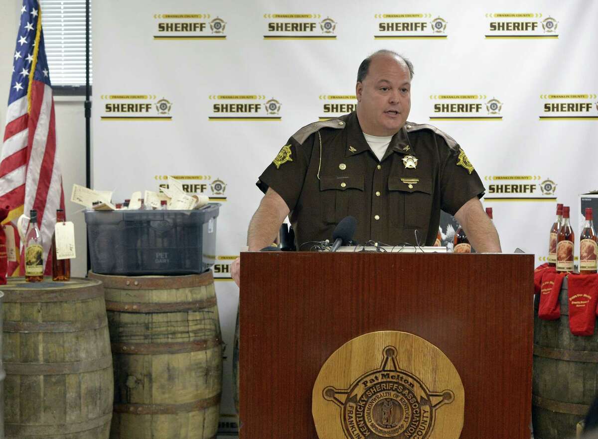 Franklin County Sheriff Pat Melton, standing in front of some of the recovered evidence, responds to a question during a press conference in Frankfort, Ky., April 21, 2015. Nine people were indicted Tuesday relating to the theft of more than $100,000 worth of Wild Turkey and Pappy Van Winkle bourbon, with thefts dating back to 2008. Prosecutors say the scheme led by rogue distillery workers lasted for years and involved tens of thousands of dollars' worth of whiskey. (AP Photo/Timothy D. Easley)