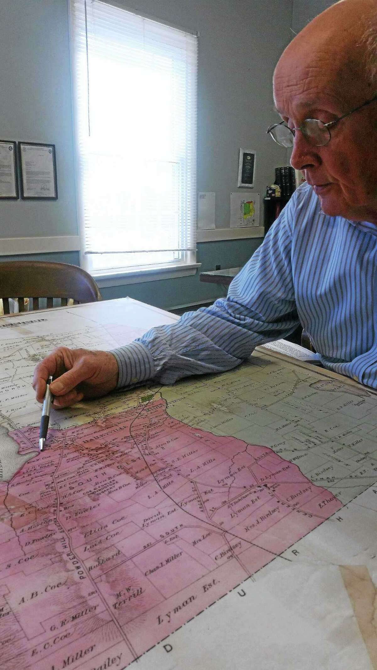 First Selectman Jon Brayshaw reviews a map of the town at his office on Wednesday.