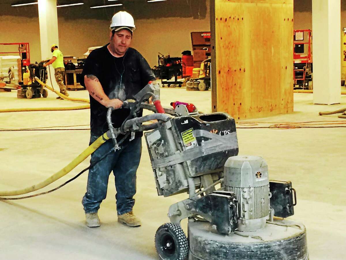 A construction worker pushes a large sander across an unfinished floor at Tanger Outlet Center at Foxwoods Tuesday.