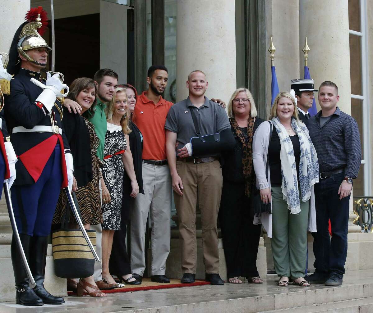 Anthony Sadler, center with orange shirt, a senior at Sacramento State University in California, U.S. Airman Spencer Stone, fourth from right, U.S. National Guardsman from Roseburg, Ore., Alek Skarlatos, third from left, and their families pose with U.S. Ambassador to France Jane D. Hartley, fourth from left, on the steps of the Elysee Palace before being awarded with the Legion of Honor Monday in Paris, France.