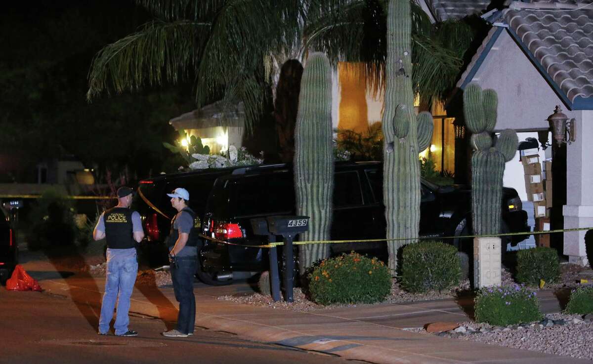 Phoenix Police Department officers stand out in front of a home where authorities say five people were killed inside after a shooting Thursday, April 16, 2015, in Phoenix. The names and ages of the three men and two women weren't immediately released, but police said they all were adults. (AP Photo/Ross D. Franklin)