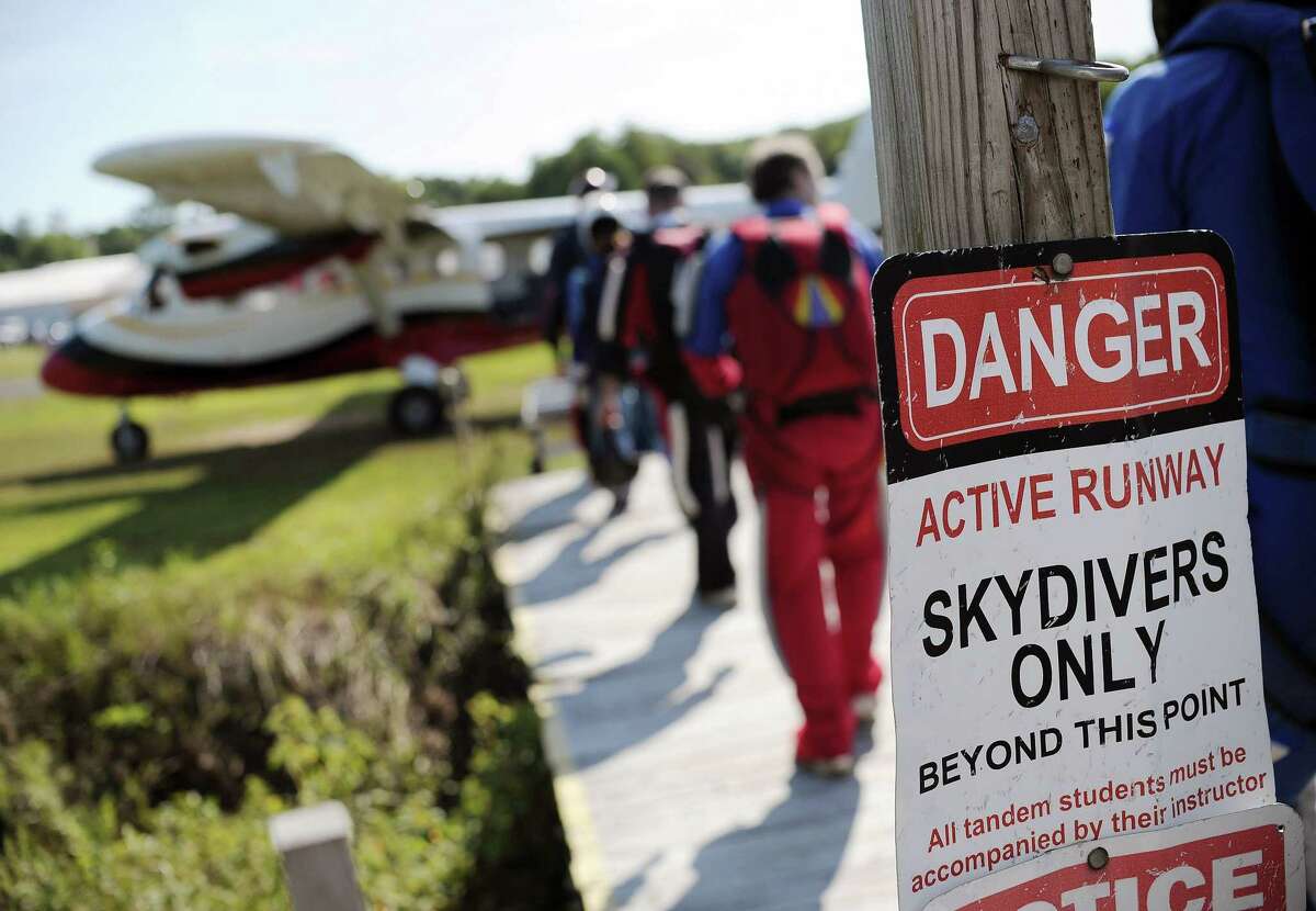 In this Friday, Aug. 7, 2015 photo, parachuters walk toward a jump plane at Ellington Airport in Ellington, Conn. Alex Kelly worked for six years for Connecticut Parachutists Inc., headquartered at the airport, and rose to president of the organization before being asked to resign in 2014. Officials of the skydiving club said Kelly is trying to buy the airport, which would give him control over the club’s lease.