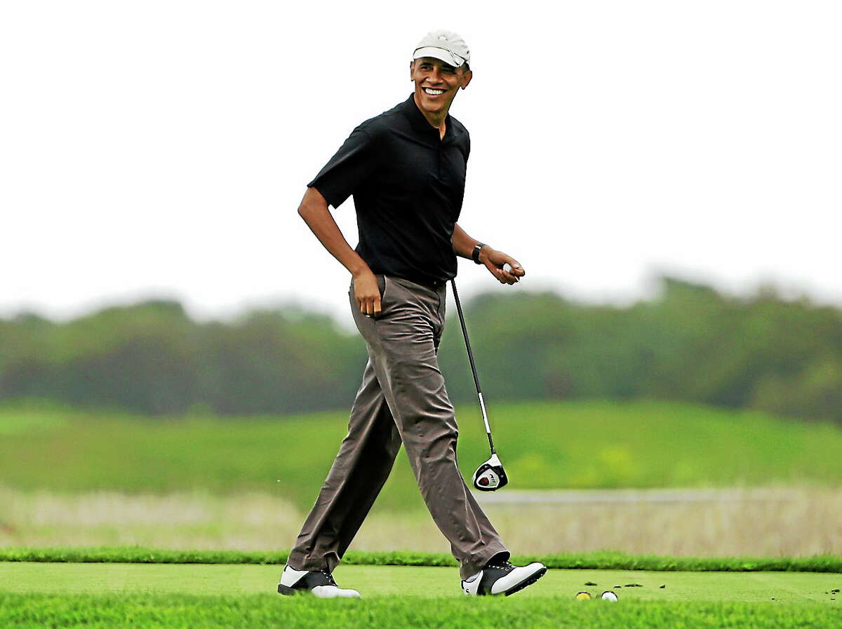 This Aug. 12, 2013 photo shows President Barack Obama as he steps onto a tee while golfing at Vineyard Golf Club in Edgartown, Mass., on the island of Martha’s Vineyard, during his vacation.