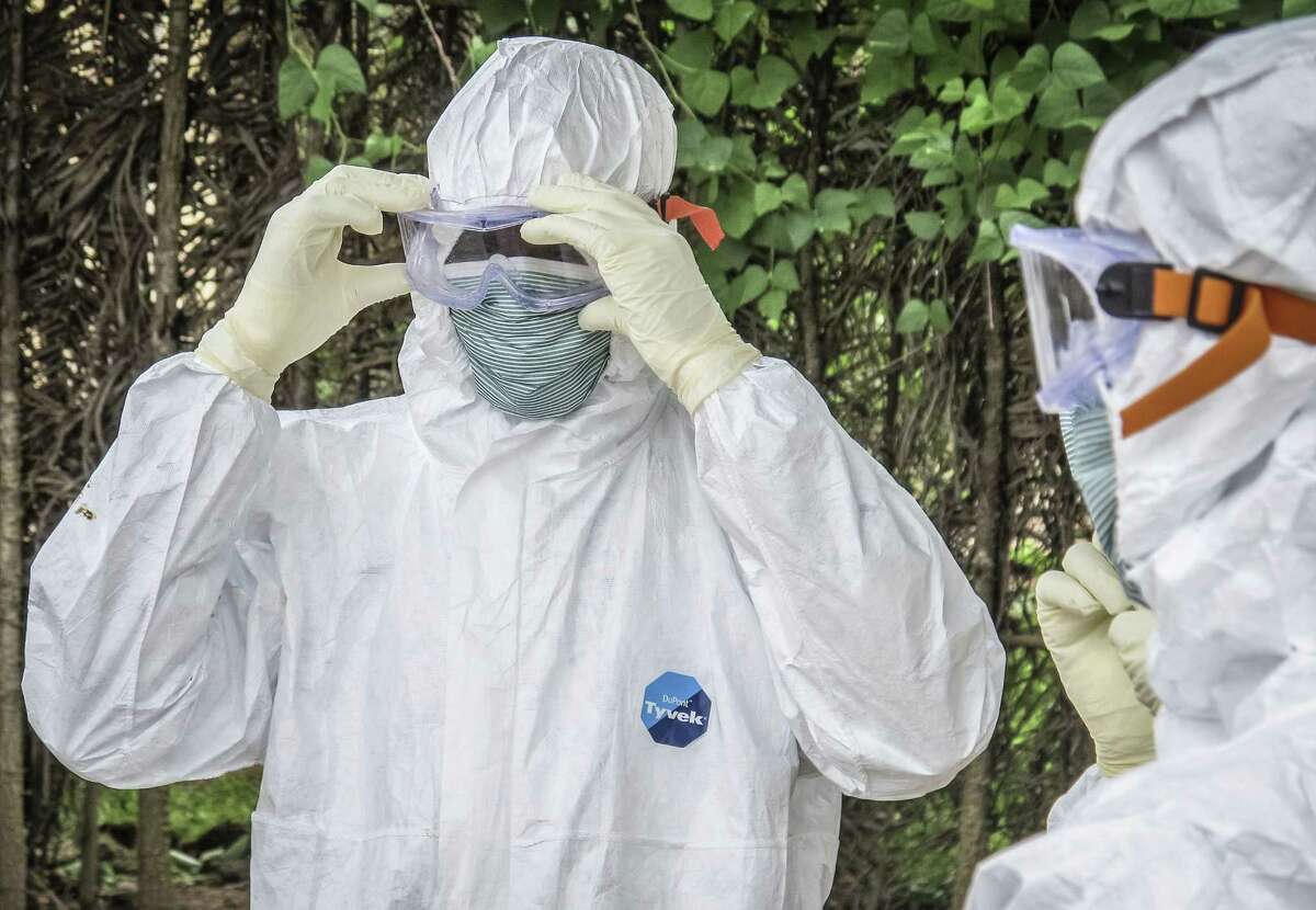 In this Tuesday, Oct. 21, 2014 photo, health workers wear protective clothing before entering the house of a person suspected to have died of Ebola virus in Port loko Community situated on the outskirts of Freetown, Sierra Leone.
