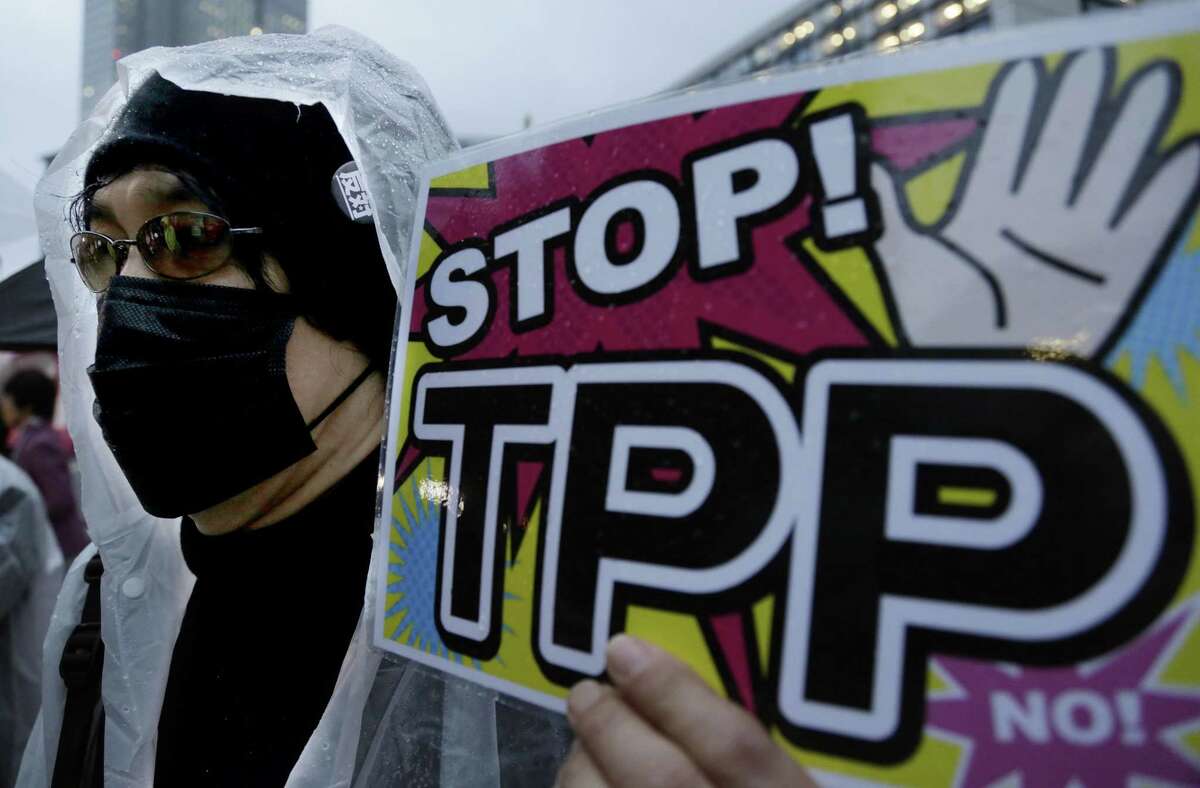In this April 22, 2014, file photo, a protester holds a placard during a rally against the Trans-Pacific Partnership in Tokyo. The United States is negotiating the ambitious trade agreement with 11 other Pacific Rim countries that’s meant to ease barriers to fast-growing Asia-Pacific markets and streamline customs rules.