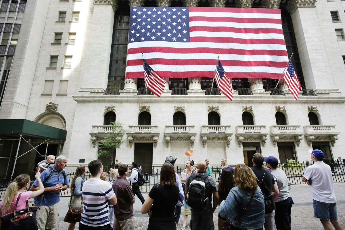 In this July 6, 2015 photo, tourists gather in front of the New York Stock Exchange. Shares sank Wednesday, Aug. 12, 2015 as China let its currency fall for a second day following a surprise devaluation that rattled global financial markets.