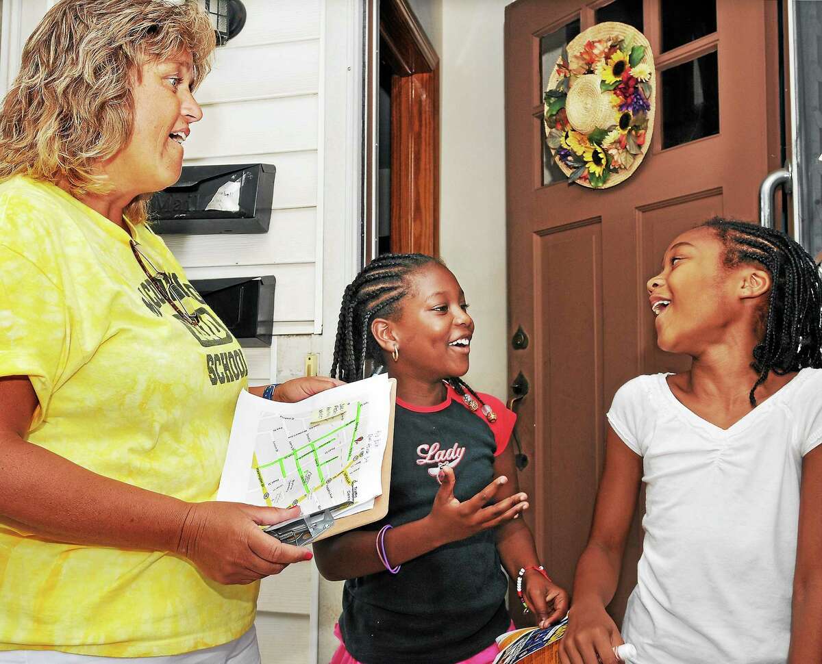 Lenicia Collins, 8, and Nasharie Davis, 9, are surprised to see Joanne Jukins, a second-grade teacher from Macdonough School visit their home on Spring Street in this 2010 file photo.