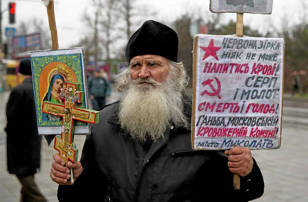A Ukrainian orthodox monk attends a rally against the breakup of the country in Simferopol, Ukraine, Friday, March 7, 2014. Ukraine lurched toward breakup Thursday as lawmakers in Crimea unanimously declared they wanted to join Russia and would put the decision to voters in 10 days. Banners read "The red star needs more blood" "Hammer and sickle re death and hunger" .(AP Photo/Vadim Ghirda)