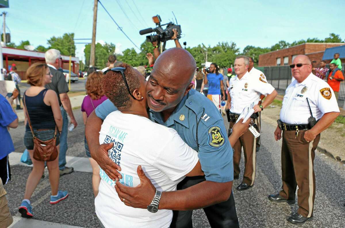 Capt. Ronald Johnson of the Missouri Highway Patrol hugs Angela Whitman, of Berkeley, Mo., on West Florissant Avenue in Ferguson, Mo., on Thursday, Aug. 14, 2014. Whitman was marching with St. Louis Metropolitan Clergy Coalition. The Missouri Highway Patrol seized control of the St. Louis suburb Thursday, stripping local police of their law-enforcement authority after four days of clashes between officers in riot gear and furious crowds protesting the death of an unarmed black teen shot by an officer. (AP Photo/St. Louis Post-Dispatch, David Carson)