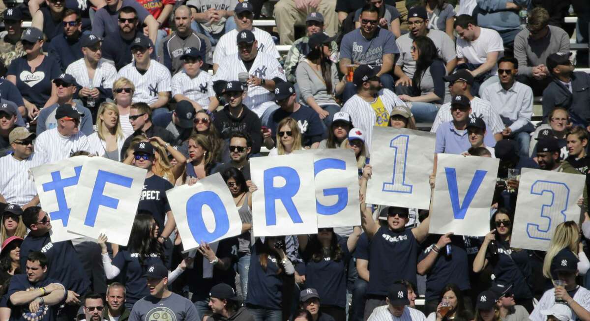 Signs in the stands encourages fans to forgive New York Yankees designated hitter Alex Rodriguez (13) as he batted in the seventh inning of an opening day baseball game against the Toronto Blue Jays in New York, Monday, April 6, 2015. Rodriguez lined out to right field in his final at bat.