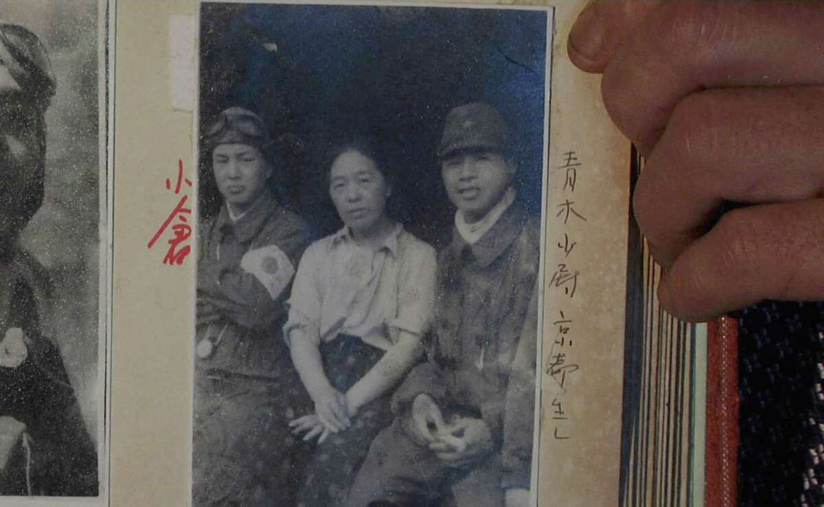 In this July 19, 2015, image taken from Associated Press Television video, Akihisa Torihama shows a 1945 photograph of his grandmother Tome Torihama, center, with Tokko pilots in Chiran in Kagoshima Prefecture, south west of Japan. Chiran served as a takeoff spot for Army pilots on a suicide attack mission in the closing days of World War II. Torihama, who died in 1992, was a mother figure for many of the pilots. Chiran is stepping up its effort to have that history remembered, and a museum there is working with the USS Missouri memorial in Hawaii to showcase the photos and letters of the dead pilots.
