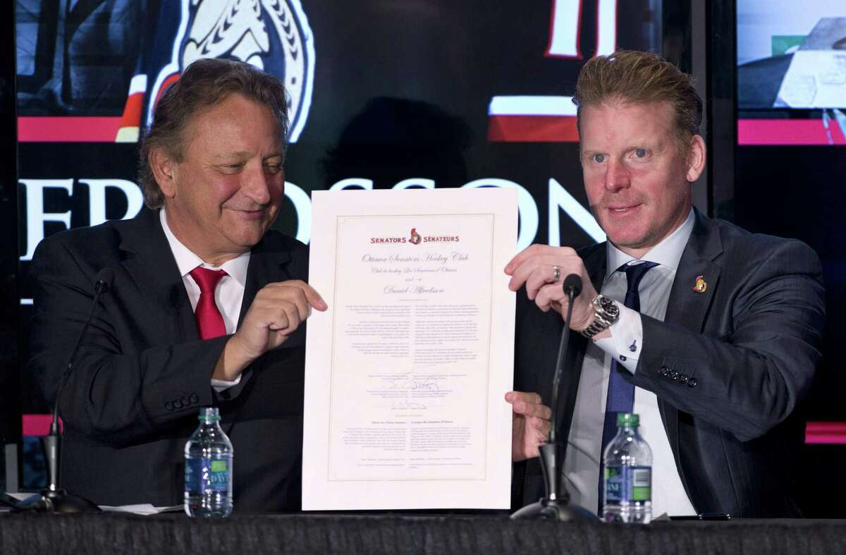 Ottawa Senators owner Eugene Melnyk, left, and Daniel Alfredsson hold up a one-day contract at a news conference announcing Alfredsson’s retirement on Thursday in Ottawa.