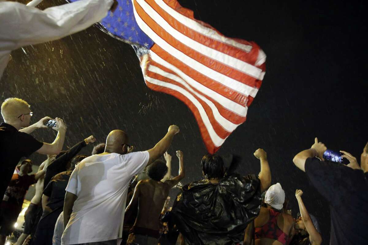 Protesters march in the rain on Aug. 9, 2015, in Ferguson, Mo. Sunday marks one year since Michael Brown was shot and killed by Ferguson police officer Darren Wilson.