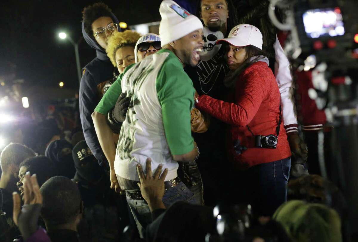 FILE - In this Nov. 24, 2014 file photo Louis Head, center front, Michael Brown’s stepfather, and Brown’s mother Lesley McSpadden, wearing sunglasses, react as they listen to the announcement that a grand jury decided not to indict Ferguson police officer Darren Wilson who fatally shot Brown. St. Louis County Police said Tuesday, Dec. 2, 2014 that authorities want to talk to Head about his angry comments as part of a broader investigation into arson, vandalism and looting that followed the Nov. 24 grand jury announcement.