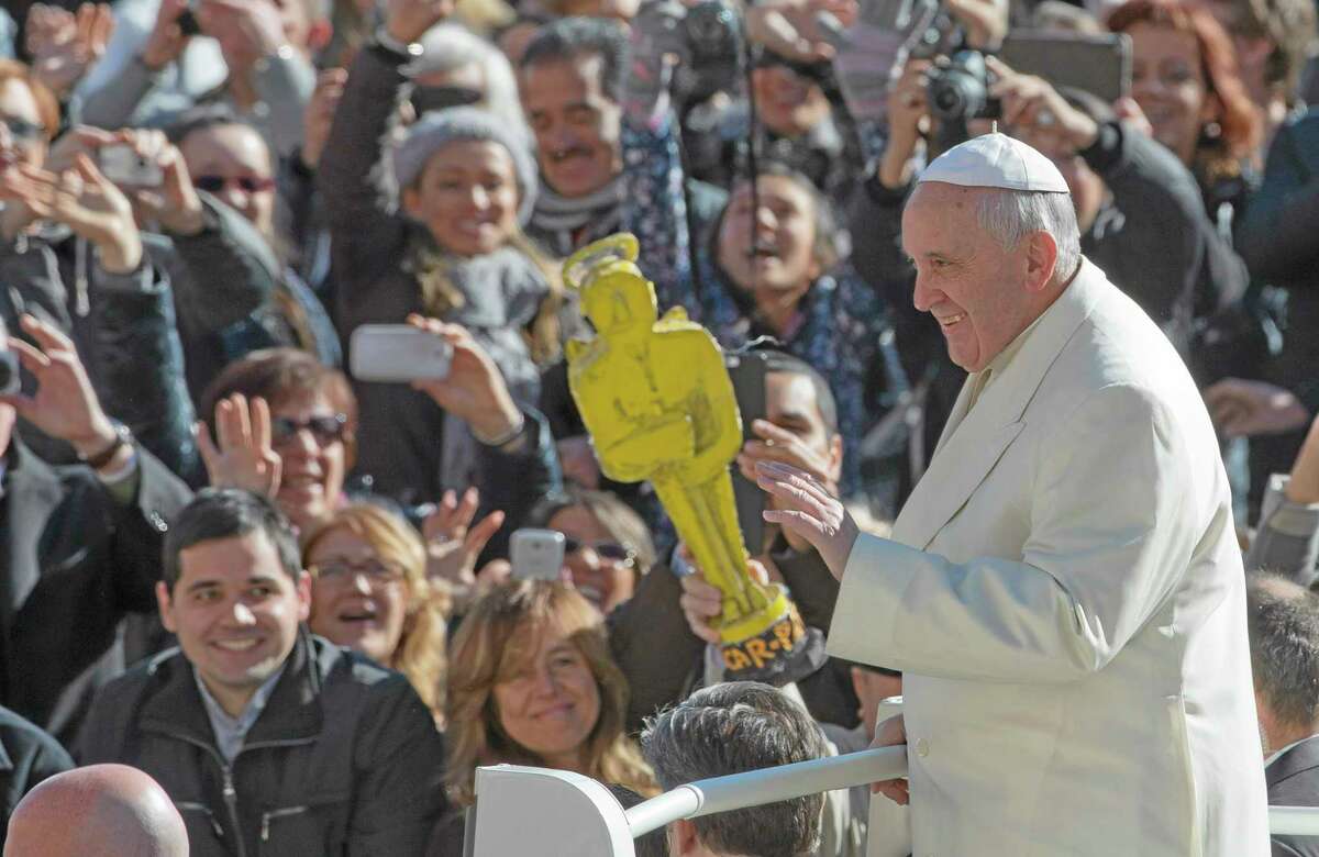 A person holds a mock Oscar statue as Pope Francis tours St. Peter's Square at the Vatican prior to the start of his weekly general audience, Wednesday, March 5, 2014. The pontiff says he finds the hype that is increasingly surrounding him "offensive." In an interview with Italian daily Corriere della Sera, Francis said he doesn't appreciate the myth-making that has seen him depicted as a "Superpope" who sneaks out at night to feed the poor. On Wednesday, a new Italian weekly hit newsstands ó a gossip magazine devoted entirely to the pope. Francis said: "The pope is a man who laughs, cries, sleeps calmly and has friends like everyone else. A normal person." (AP Photo/Alessandra Tarantino)