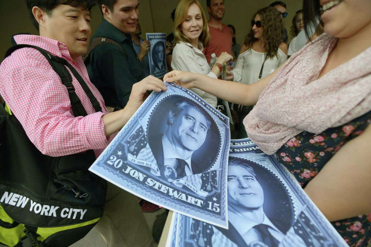 People receive posters while in line for the taping of the final episode of “The Daily Show” with Jon Stewart, Thursday, Aug. 6, 2015, in New York.