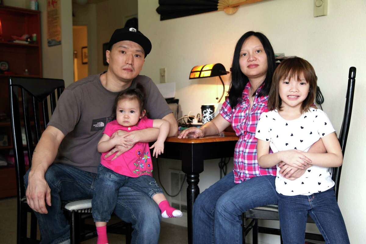 Korean adoptee Adam Crapser, left, poses with daughters, Christal, 1, Christina, 5, and his wife, Anh Nguyen, in the family's living room in Vancouver, Wash. on March 19, 2015. Crapser, whose adoptive parents neglected to make him a U.S. citizen, will face an immigration judge and could be separated from his family and deported to South Korea, a country he does not know. (AP Photo/Gosia Wozniacka)
