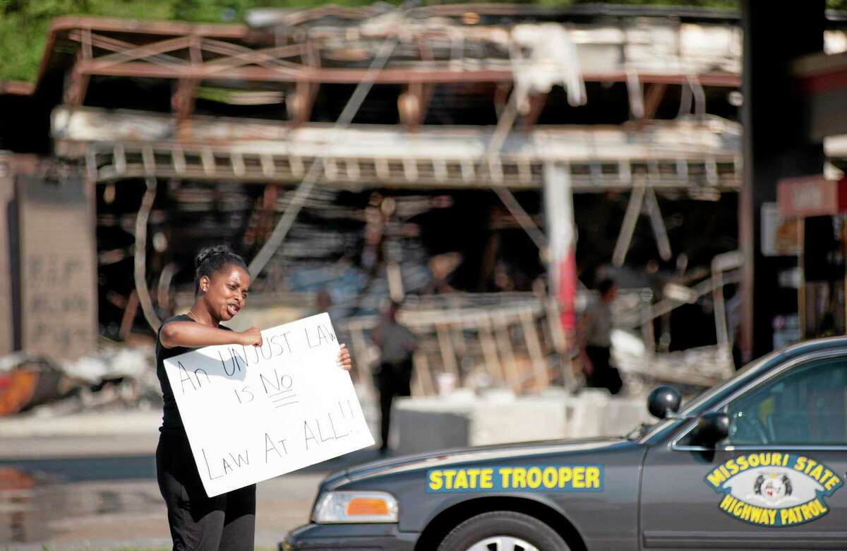 Protesters appeal to motorists for support while rallying on Monday, Aug. 11, 2014 in front of the QT gas station in Ferguson, Mo. that was looted and burned during rioting overnight that followed a candlelight vigil honoring 18-year-old Michael Brown, who was shot Aug. 9, 2014 by Ferguson police officers.