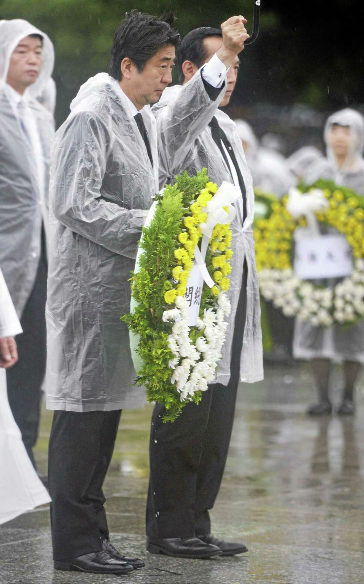 Japan's Prime Minister Shinzo Abe, center left, offers flowers to the atomic bomb victims during a ceremony at the Hiroshima Peace Memorial Park in Hiroshima, western Japan, Wednesday, Aug. 6, 2014. Japan marked the 69th anniversary Wednesday of the atomic bombing of Hiroshima. (AP Photo/Kyodo News) JAPAN OUT, MANDATORY CREDIT