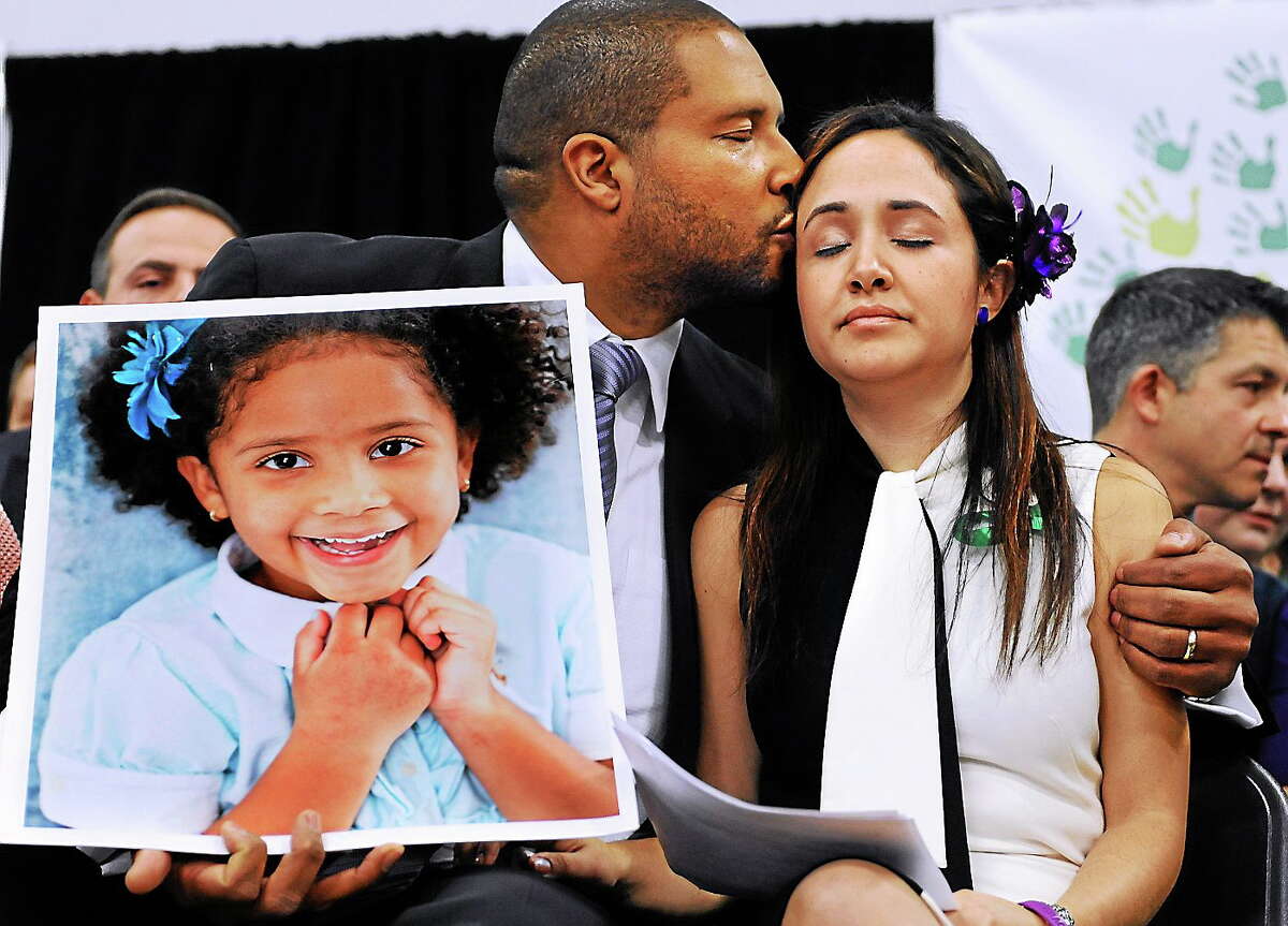 Jimmy Greene, left, kisses his wife Nelba Marquez-Greene as he holds a portrait of their daughter, Sandy Hook School shooting victim Ana Marquez-Greene, at a news conference in Newtown, Conn., on Jan. 14, 2013.