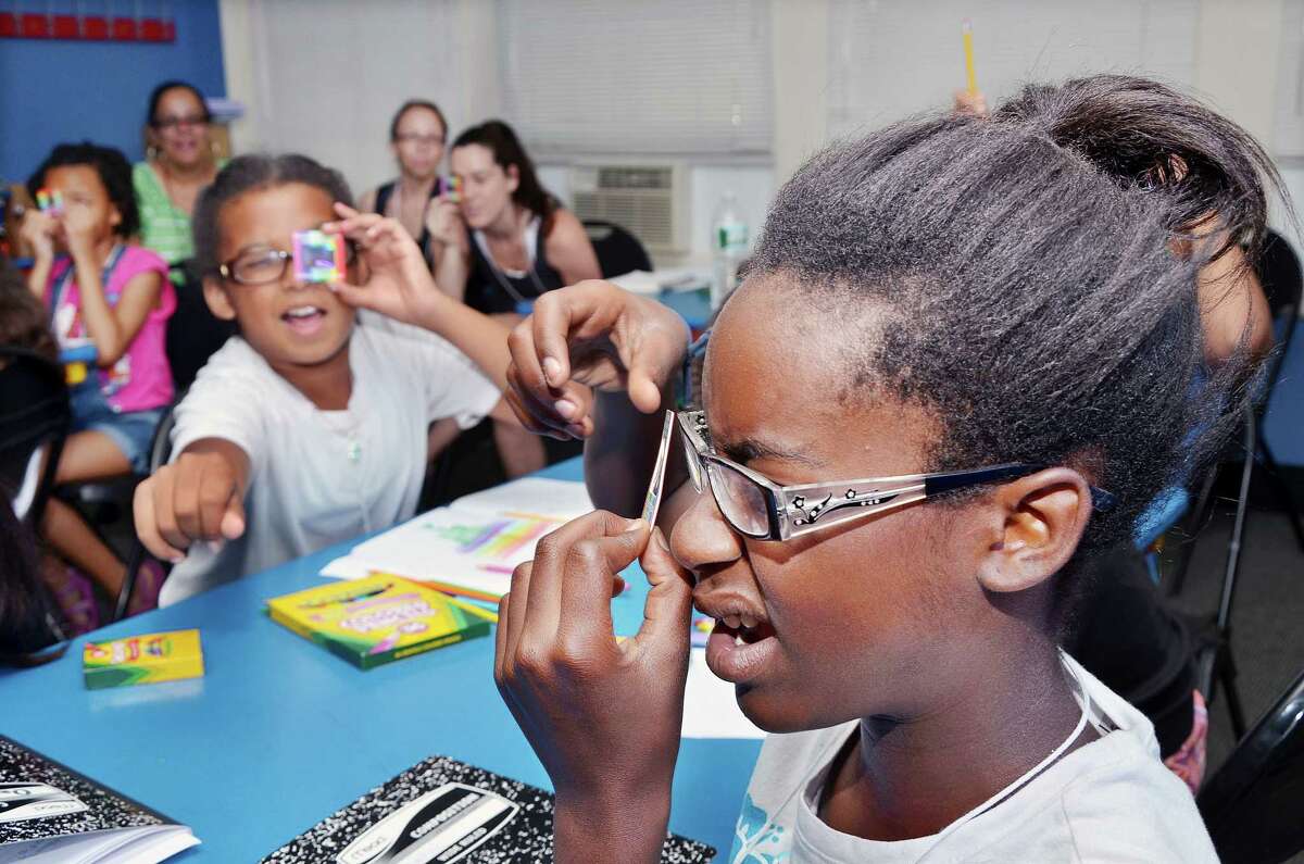 Catherine Avalone - The Middletown Press Tyshala Morris-Hayes, 11, at right and Julia Martinez, 10, react to using a linear diffraction grating to see scattered red laser light during a class taught by Wesleyan University physics professor Christina Othon at the Girls in Science Summer Camp at Green Street Arts Center in Middletown. Wesleyan faculty and students taught 10 girls about mutations, light, color, DNA, gardens, insects, created germ plates, and designed a bacteria in the art room throughout the week.