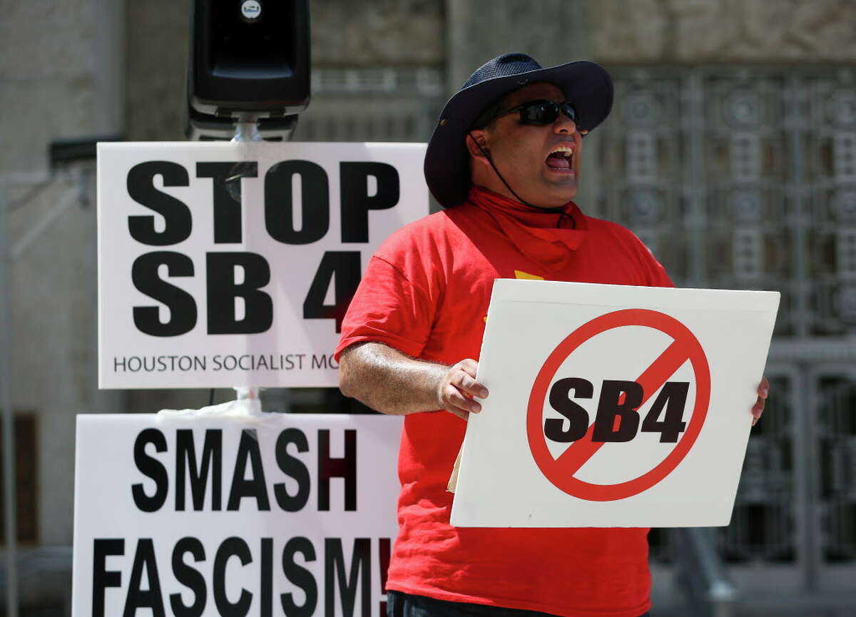 An anti-Senate Bill 4 supporter chants while similar-minded groups gather at Houston City Hall for a rally Saturday, Aug. 12, 2017, in Houston. Groups of SB4 supporters also gathered across Walker Street to speak their mind.
