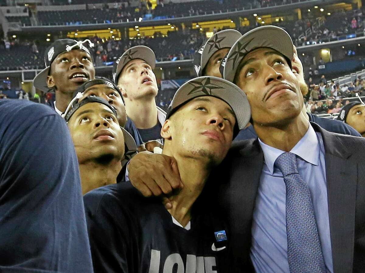 Connecticut head coach Kevin Ollie right, embraces guard Shabazz Napier as the team watches a highlight video of March Madness after their team beat Kentucky 60-54 at the NCAA Final Four tournament college basketball championship game Monday in Arlington, Texas. (AP PHOTO/DAVID J. PHILLIP)