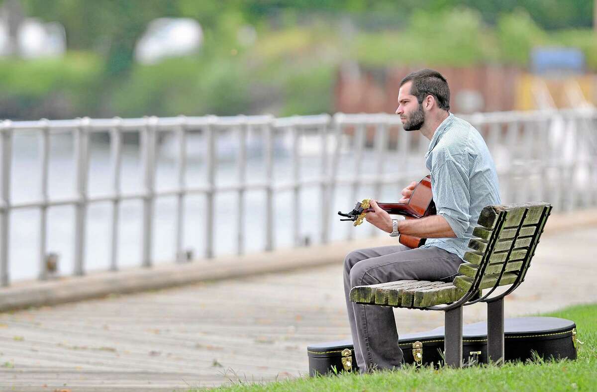 Middletown resident Joseph Brayman plays the blues on his guitar at Harbor Park in Middletown Friday afternoon. Brayman said, "It's a nice day to play by the river. Summer is coming to an end." (Catherine Avalone - The Middletown Press)