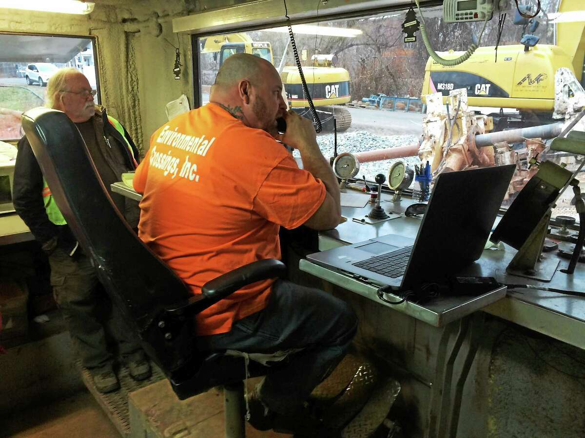 Justin Love directs Mattabassett Regionalization drilling operations in Middletown near the Arrigoni Bridge as Gregg Morton looks on.