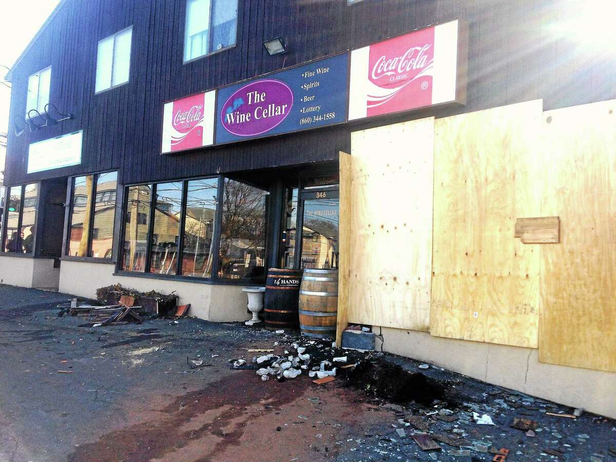 Alex Gecan - The Middletown Press Plywood covers the windows and barrels bar the entrance to The Wine Cellar at 346 South Main St. after a car plowed into the front of the building late Wednesday night.