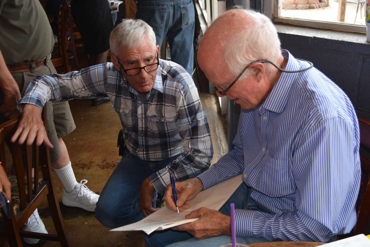 “Leap of Faith” director Richard Pierce (right) signs a movie script for Greg Cronholm on Saturday during a reception in the Broadway Brew marking the 25th anniversary of the Steve Martin film being shot in Plainview. The script was left behind in Cronholm’s office, which became the office used by Liam Neeson’s character. Cronholm was AgriLife Extension entomologist, and the Extension Building became the sheriff’s office in the film.