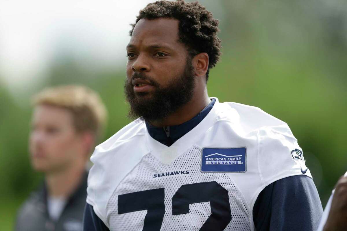 FILE - In this June 13, 2017, file photo, Seattle Seahawks defensive end Michael Bennett walks off the field following NFL football practice in Renton, Wash. Bennett says he will sit during the national anthem this season to protest social injustice and segregation. Bennett sat on the visiting bench during "The Star-Spangled Banner" on Sunday, Aug. 13, 2017, before the Seahawks' preseason opener against the Los Angeles Chargers, a decision he made prior to protests by white supremacists at the University of Virginia over the weekend. But what happened in Charlottesville, Virginia, including the death of a young woman when she was struck by a car deliberately driven into a group of counter-protesters on Saturday, solidified Bennett's decision. (AP Photo/Ted S. Warren, File)