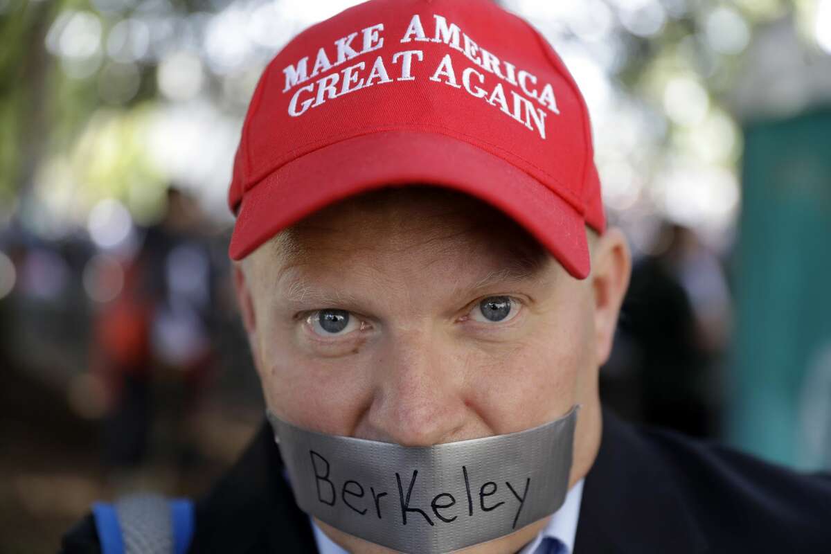 Daryl Tempesta tapes a sign over his mouth in protest during a demonstration Thursday, April 27, 2017, in Berkeley, Calif. Demonstrators gathered near the University of California, Berkeley campus amid a strong police presence and rallied to show support for free speech and condemn the views of Ann Coulter and her supporters. (AP Photo/Marcio Jose Sanchez)