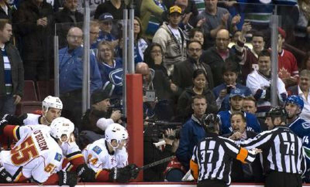 Referees get in the way of Vancouver Canucks head coach John Tortorella as he screams at the Calgary Flames bench during first period of a Saturday game.
