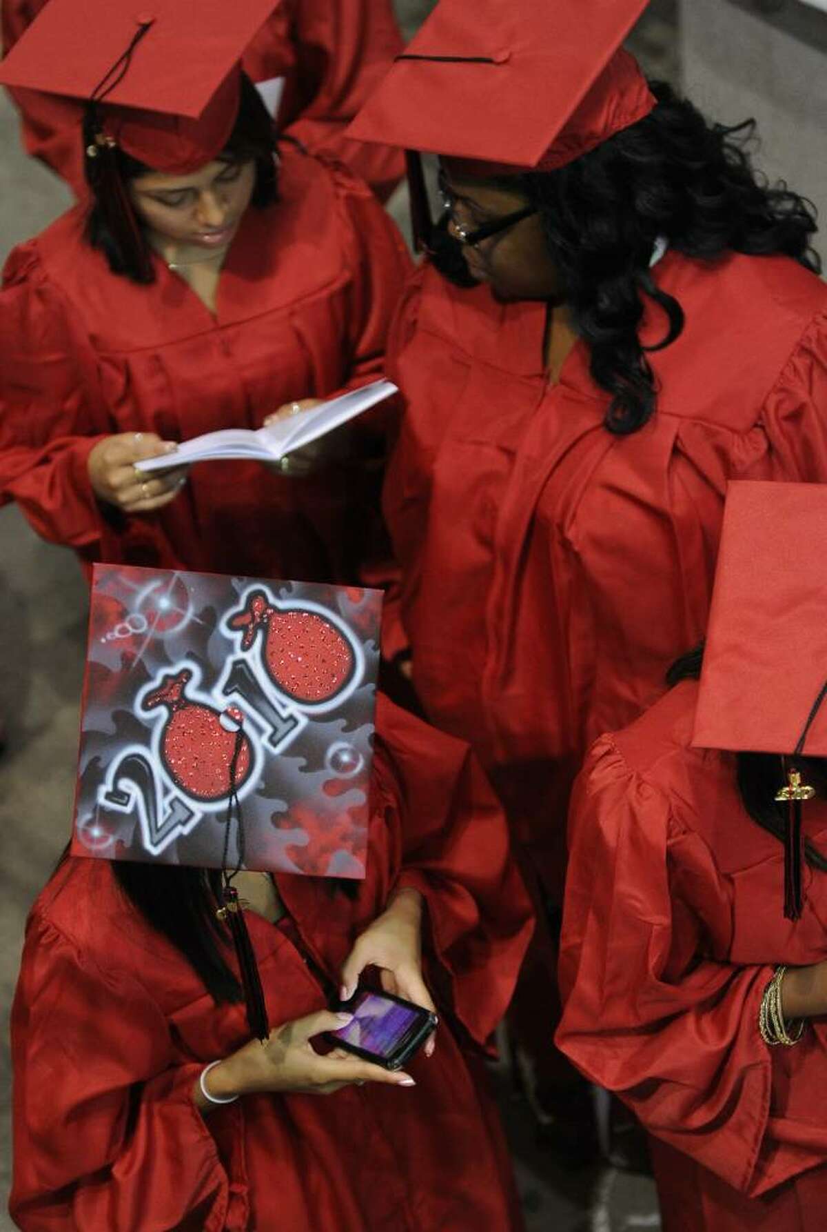 Graduate Jennifer Molina, bottom left, texts a message before heading in to be seated with her classmates, before the start of Central High School's Graduation Exercises at the Arena at Harbor Yard in downtown Bridgeport, Conn. on Thursday June 17, 2010.