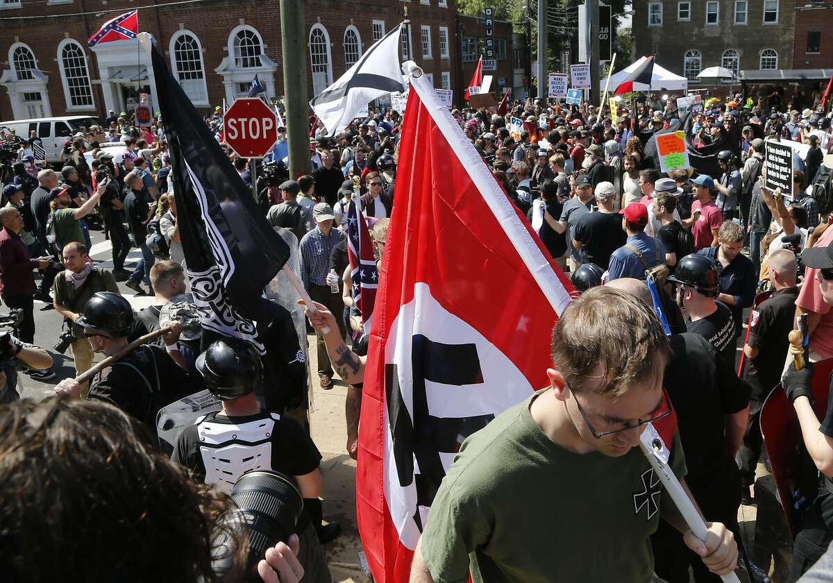 This Saturday, Aug. 12, 2017 image shows s white supremacist carrying a NAZI flag into the entrance to Emancipation Park in Charlottesville, Va. (AP Photo/Steve Helber)