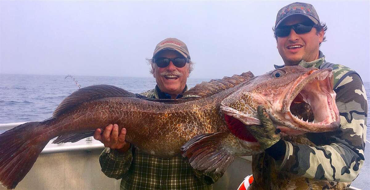 Yancey Forrest-Knowles, left, ventured from the Bay Area to Sitka, Alaska for a chance of what is not typically available in California — like this 72-pound lingcod, which he released unharmed back into the ocean after this photograph. Josh Birch, also from the Bay Area, helps him hoist the giant fish.