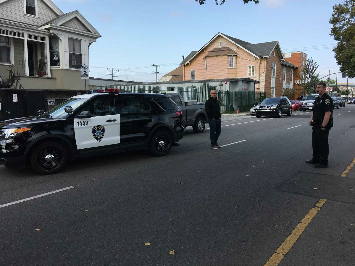 An agent with Homeland Security Investigations and an Oakland police officer stand on 27th Street during a search of a residence on the street.