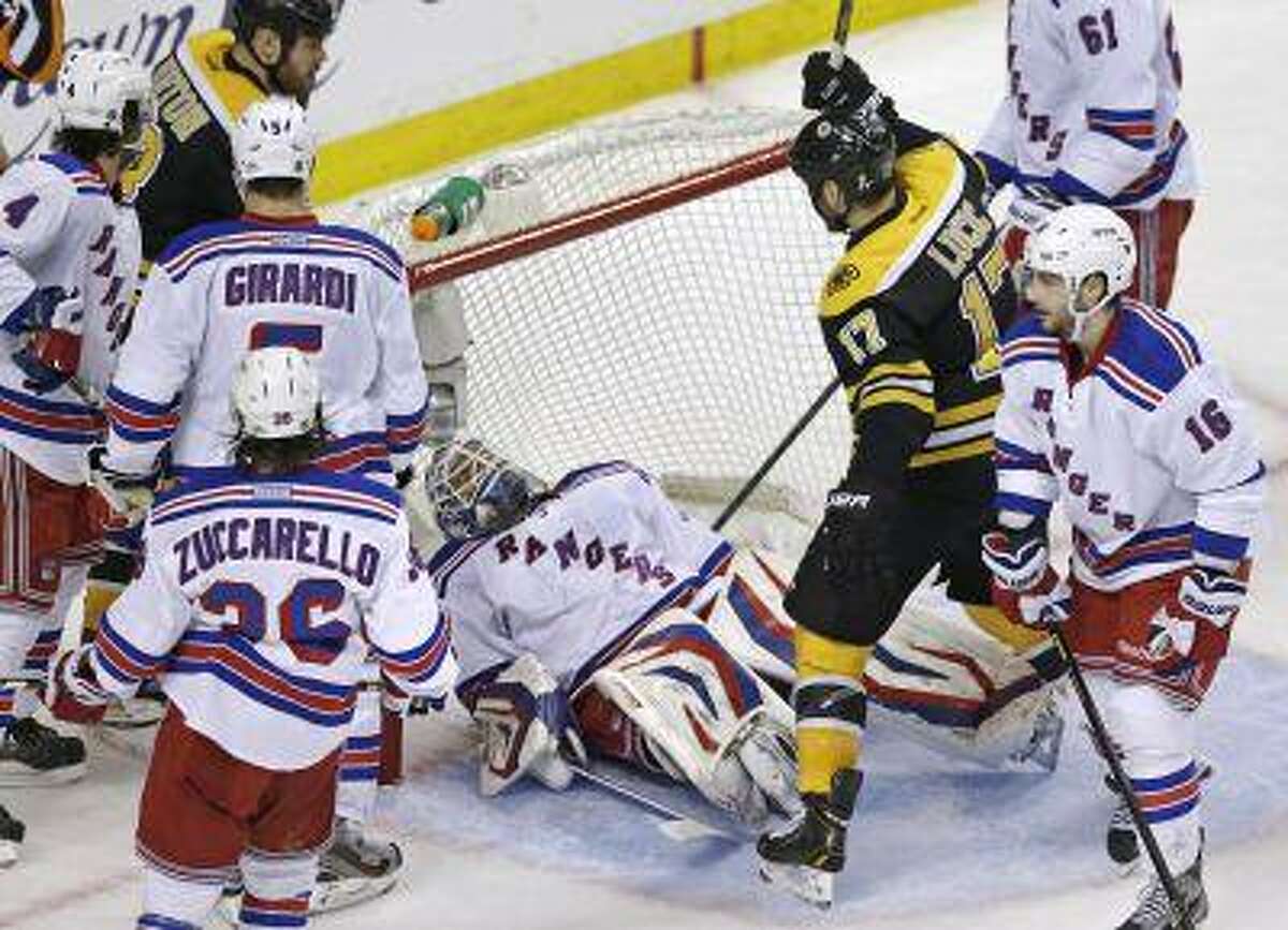 Boston Bruins left wing Milan Lucic (17) raises his stick to celebrate a goal by teammate Zdeno Chara (not shown) as New York Rangers goalie Henrik Lundqvist, center, falls onto his back during the second period in Game 1 of an NHL hockey playoffs Eastern Conference semifinal game in Boston, Thursday, May 16, 2013.